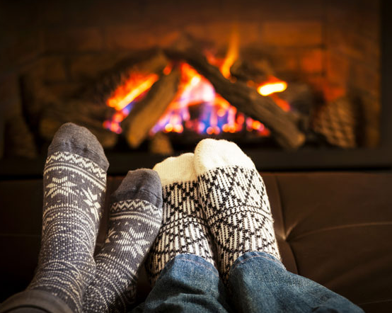 the image shows a fire place that is lit with people enjoying the heat